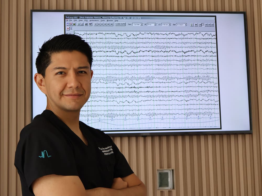 Dr. Julio César Ramírez Reyes junto a un registro de electroencefalograma
